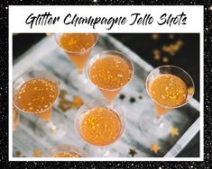 several glasses filled with champagne sitting on top of a silver tray covered in gold flakes