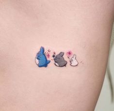 a woman's stomach has three small tattoos on it, one with rabbits and the other with flowers