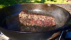 a steak is cooking in a skillet on the grill