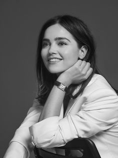 a black and white photo of a woman with her hand on her shoulder smiling at the camera