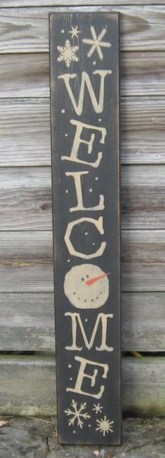 a wooden sign with the word welcome written in white on it and snowflakes