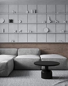 a modern living room with grey couches and shelving on the wall behind it