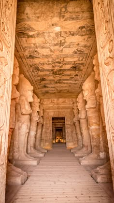 the interior of an ancient egyptian temple with carved columns and statues on either side of the entrance