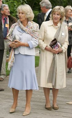 two women standing next to each other in front of people on a wooden deck outside