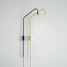 a black and yellow lamp on a white wall next to a light pole with two lights