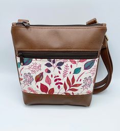 "Handcrafted small crossbody bag featuring a pretty fall leaves focus fabric and trimmed in a soft brown vinyl. This bag features a fully adjustable crossbody strap so you can wear over the shoulder or crossbody. Bag also has a waterproof canvas lining and front zippered pocket. Finished off with antique bronze hardware. This listing is for the bag ONLY. Matching accessories are available in the \"Accessories\" section of my shop. 8.5 Inches Tall 8.5 Inches Wide (across bottom) 2 Inches deep Fro Crossbody Bag Pattern, Vinyl Bag, Small Crossbody Purse, Bronze Hardware, Christmas Gift For Her, Soft Brown, Matching Accessories, Small Crossbody Bag, Christmas Bags