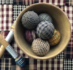 a bowl filled with different colored balls on top of a checkered table cloth next to a baseball bat