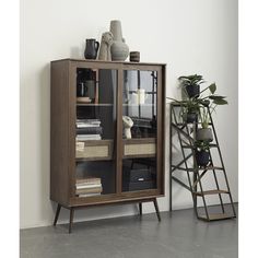 a book shelf with books and vases on it next to a potted plant