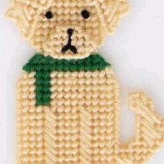 a crocheted teddy bear with a green ribbon around it's neck and eyes