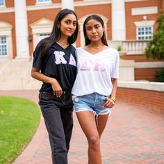 two young women standing next to each other in front of a building