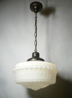 a light fixture hanging from a ceiling in a room with white walls and a black chain