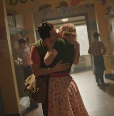 two people are kissing each other in front of a sign that says don't stop