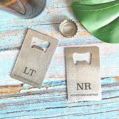 two bottle openers sitting next to each other on top of a wooden table with leaves