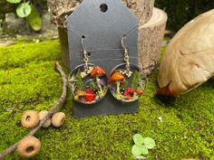 These exquisite handmade earrings are truly a one-of-a-kind piece of nature-inspired art. Crafted from resin and adorned with real mushrooms, pressed ferns, delicate flowers, tiny acorns, moss, and a charming ladybug, these earrings are a special gift for anyone who appreciates nature's beauty. Whether you're shopping for your teacher, best friend, daughter, mom, or girlfriend, they are sure to treasure these unique earrings. Give the gift of nature and style with these stunning and whimsical earrings. 💙 Beautiful and unique design 💙 natural materials (real mushrooms, moss and fern) 💙 Hypoallergenic sterling silver or gold filled hooks 💙 Both rubber & soft-close backs provided 💙Lightweight and comfortable 💙Entirely handmade MATERIALS. The earrings are made of UV resin, real dry mushr Nature-inspired Drop Earrings With Natural Inclusions, Nature-inspired Dangle Earrings With Mushroom Design, Mushroom Design Dangle Earrings As Gift, Mushroom Design Dangle Earrings For Gift, Nature-inspired Dangle Jewelry With Mushroom Design, Handmade Nature-inspired Resin Earrings, Nature-inspired Mushroom Design Dangle Jewelry, Unique Mushroom Design Earrings As Gift, Unique Mushroom Design Earrings For Gift