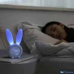 a woman laying in bed with an alarm clock on the nightstand next to her head