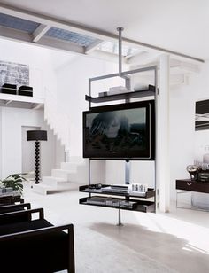 a living room filled with furniture and a flat screen tv mounted on a wall next to a stair case