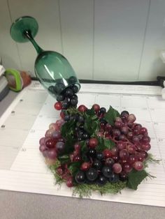 grapes and other fruits are on a cutting board with a green spoon in the middle