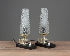 two glass candlesticks sitting on top of a wooden table