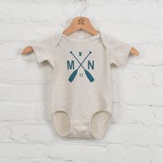 Introducing our Twin Lakes Onesie, the perfect gift for the little one in your life. This oatmeal onesie features a playful teal paddle graphic, making it cute and neutral essential. (Plus, it's so soft and cozy!) - 100% Cotton - Machine wash cold/tumble dry low - Designed and printed in USA - Imported Retail: $22 Casual Cream Onesie For Playtime, Cream Casual Onesie For Playtime, Casual Cream Onesie For Loungewear, Key And Peele, Twin Lakes, Area Codes, Corporate Gifts, Summer Collection, Little One