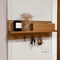 a wooden shelf with keys and bottles hanging from it's sides next to a door