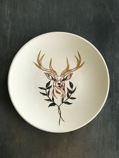 a white bowl with a deer's head painted on it