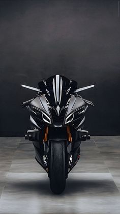 a black and silver motorcycle is parked in a dark room with no one around it