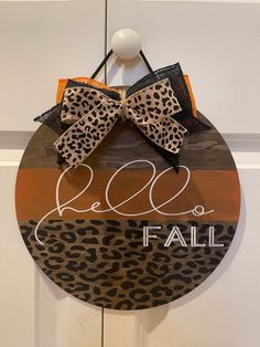 a leopard print sign hanging on a door with the word fall written in white ink