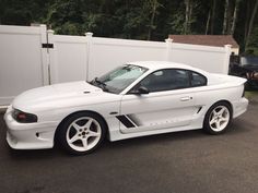 a white sports car parked in front of a fence