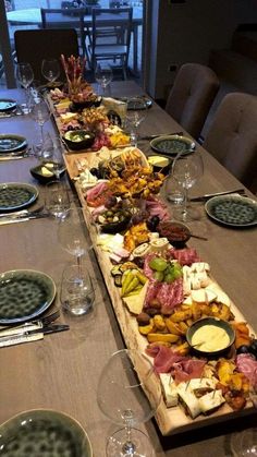 a long wooden table with plates and glasses on it, along with other food items