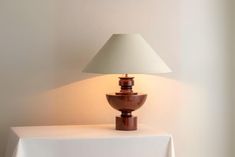 a lamp sitting on top of a table next to a white cloth covered tablecloth