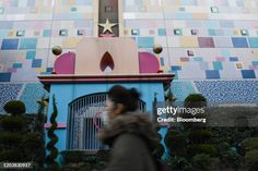 a woman walking past a colorful building with a star on it's roof and windows