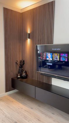 a flat screen tv sitting on top of a wooden shelf in front of a wall