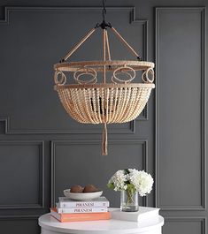 a basket hanging from the ceiling over a table with books and vases on it