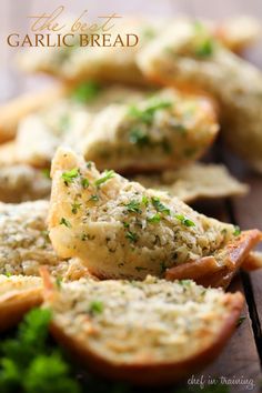 closeup of garlic bread with parsley sprinkled on top and other food items in the background