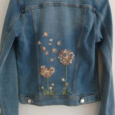 a denim jacket with dandelions embroidered on it