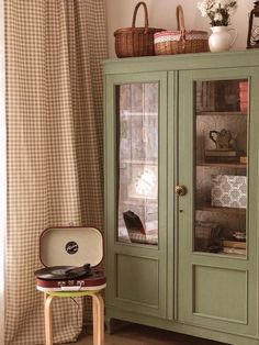 a green china cabinet sitting next to a window