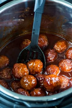 the meatballs are being cooked in the slow cooker with a ladle to stir them