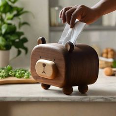 a wooden bear tissue dispenser sitting on a counter top next to a cutting board