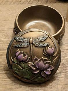 a metal container with flowers and dragonflies on it