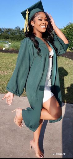 a woman in a graduation cap and gown is posing for the camera with her hand on her hip