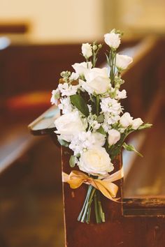 a bouquet of white flowers sitting on top of a wooden box in front of a pew