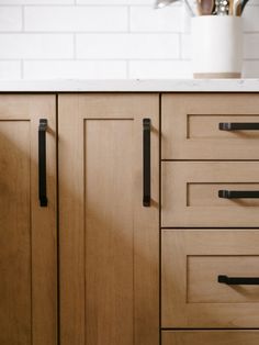 a kitchen with wooden cabinets and black handles