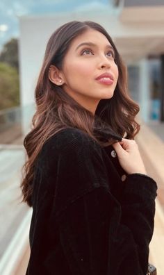 a woman is standing outside with her hand on her shoulder and looking up at the sky