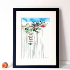 a watercolor painting of flowers is displayed on a shelf next to an orange ball