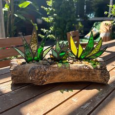 some green and yellow glass plants sitting on top of a piece of drifty wood