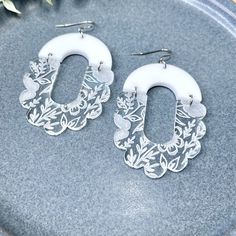 "Grab and go, wear with anything earrings! That's what these are! Clear acrylic is engraved on the back to reveal beautiful florals from the clear and smooth frontside. Featuring a white acrylic arch to complete this oval scalloped hoop look. Casual and minimalist with a bit of fancy to make you feel gorgeous!  Measures approximately 2\" from stainless steel hooks and jump rings. Hypoallergenic and safe for sensitive ears." White Oval Hoop Earrings For Gift, White Teardrop Hoop Earrings As Gift, Clear Small Hoop Earrings As Gift, White Small Hoop Earrings For Anniversary, White Small Hoop Jewelry For Anniversary, White Oval Hoop Earrings For Weddings, Etched Hoop Earrings As Gift, White Hoop Jewelry For Jewelry Making, Handmade Clear Hoop Earrings As Gift