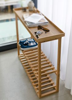 a wooden table with several pairs of shoes on it and a mirror in the background