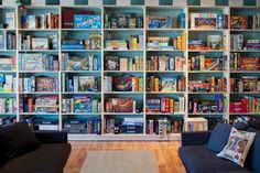 a living room filled with furniture and bookshelves covered in lots of different types of games