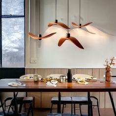 a dining room table with four lights hanging over it