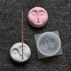 two clay faces and a toothbrush are on the floor next to each other,